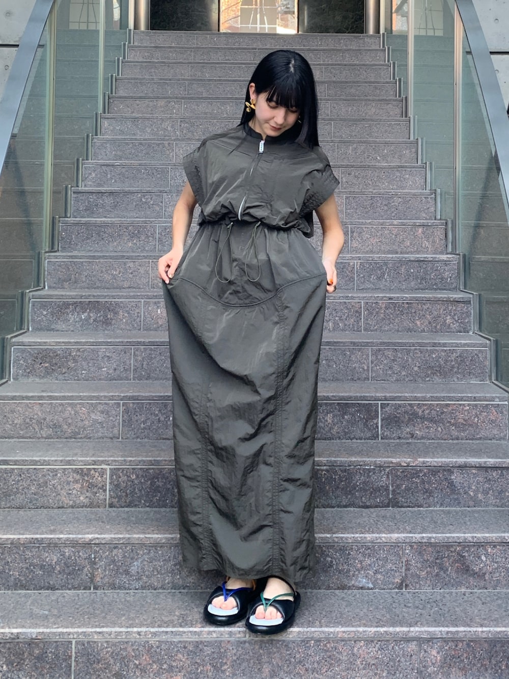 グリーン系のワンピース、その他のサンダル、ゴールド系のピアス（両耳用）を着用したレディースの春コーディネートの2枚目の写真