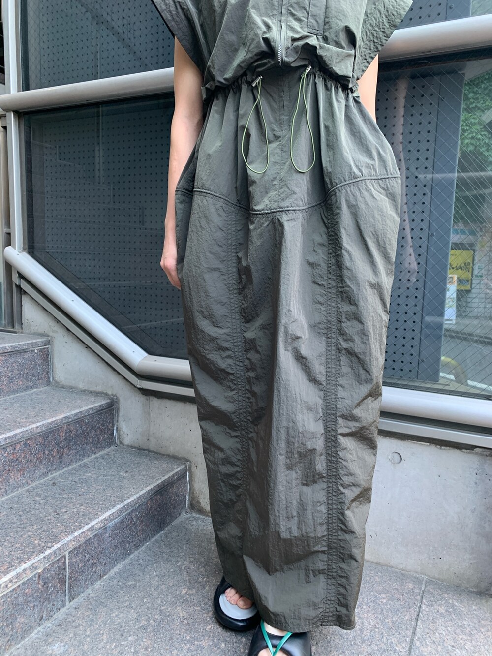 グリーン系のワンピース、その他のサンダル、ゴールド系のピアス（両耳用）を着用したレディースの春コーディネートの6枚目の写真