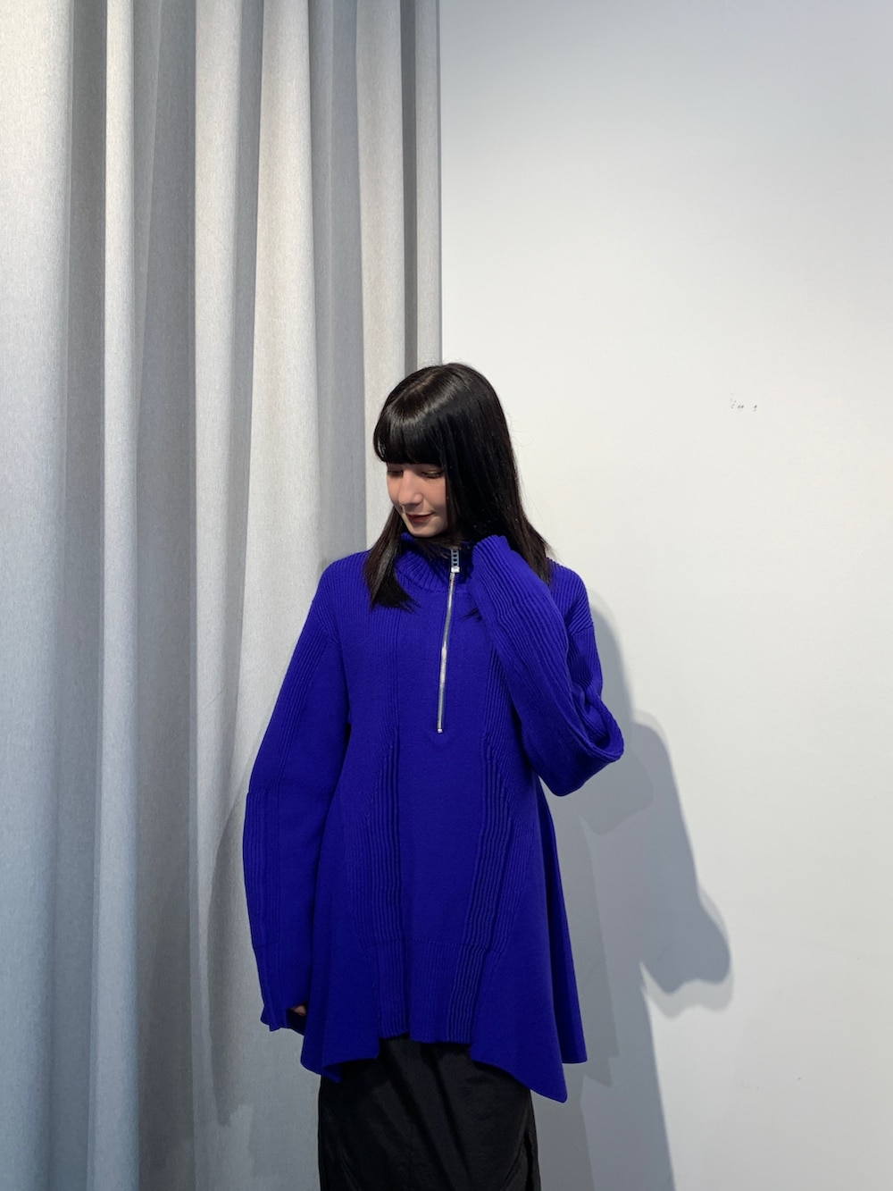 ブラック系のニット/セーター、ブラック系のスカート、ブラック系のブーツを着用したレディースの夏コーディネートの2枚目の写真