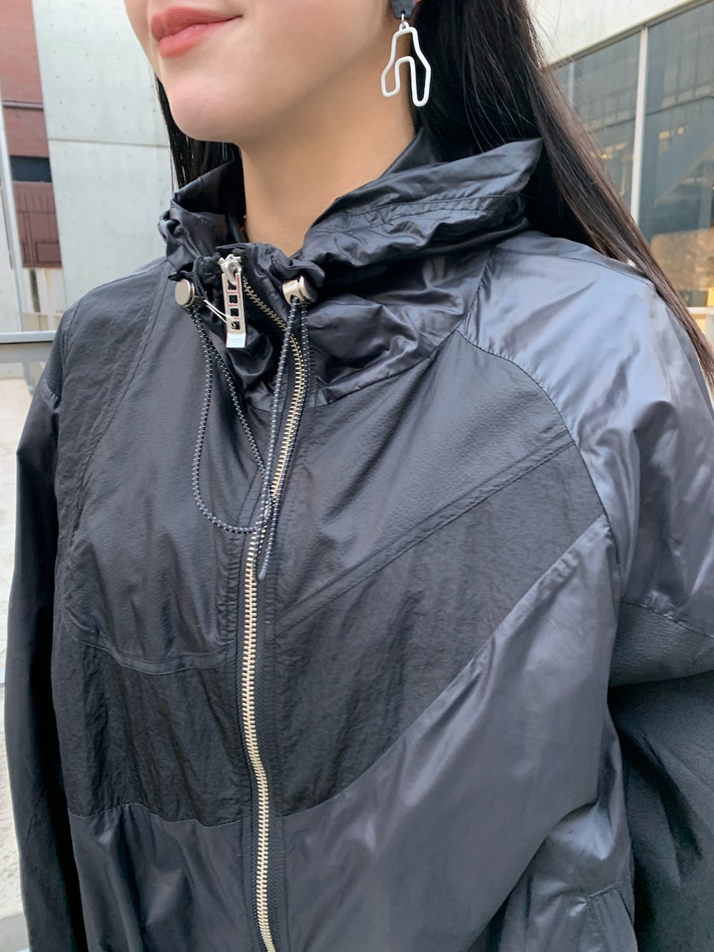 ブラック系のナイロンジャケット、ブラック系のジャンパースカート、ブラック系のサンダルを着用したレディースの冬コーディネートの3枚目の写真