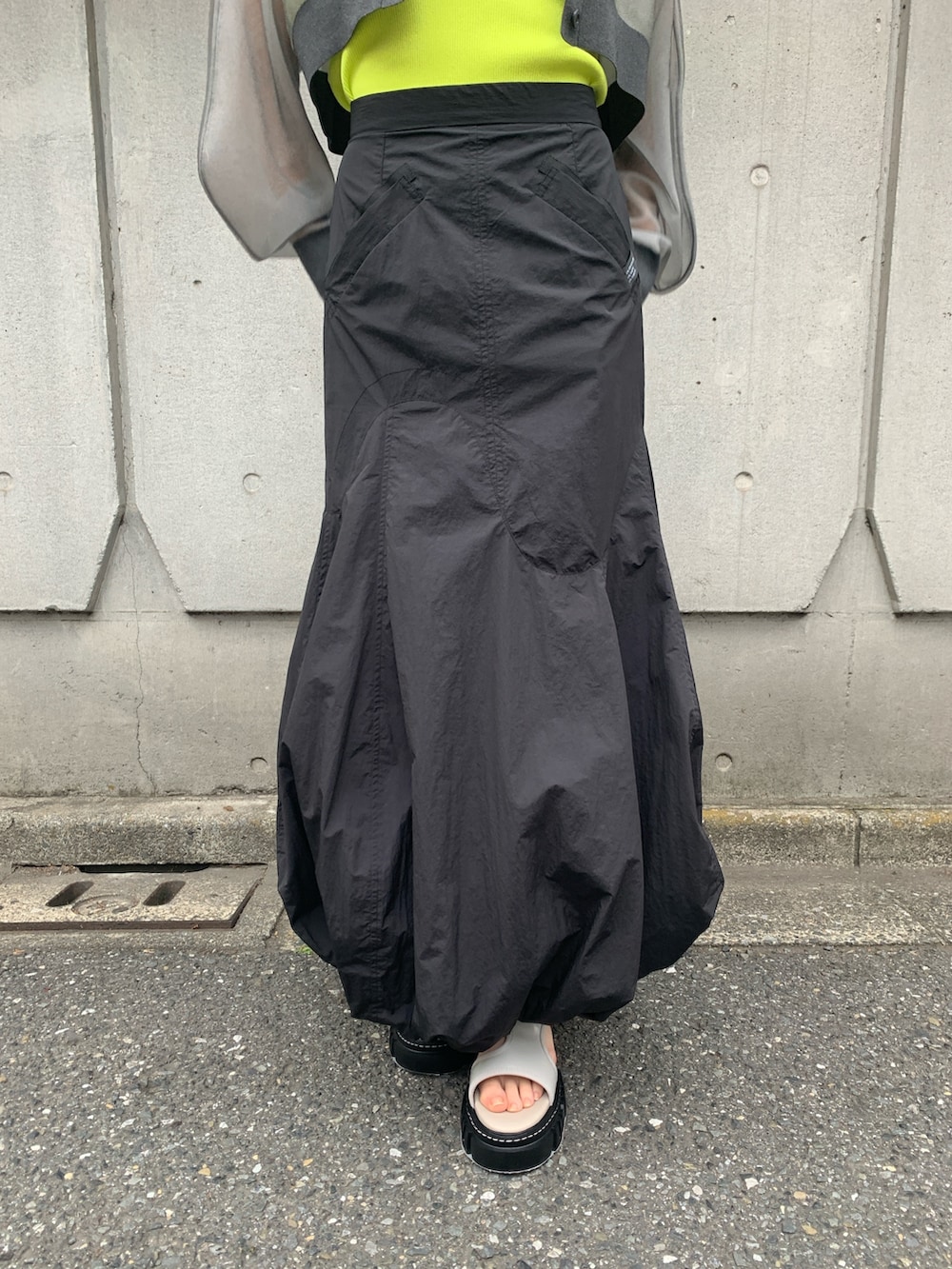 グレー系のカーディガン/ボレロ、イエロー系のタンクトップ、ブラック系のスカートを着用したレディースの春コーディネートの5枚目の写真