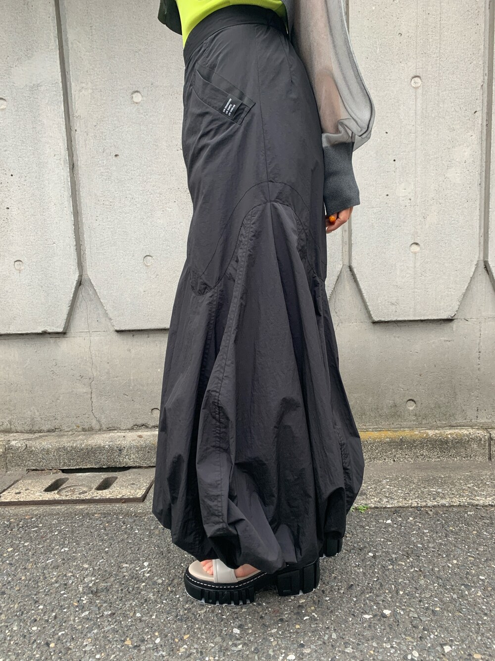 グレー系のカーディガン/ボレロ、イエロー系のタンクトップ、ブラック系のスカートを着用したレディースの春コーディネートの4枚目の写真