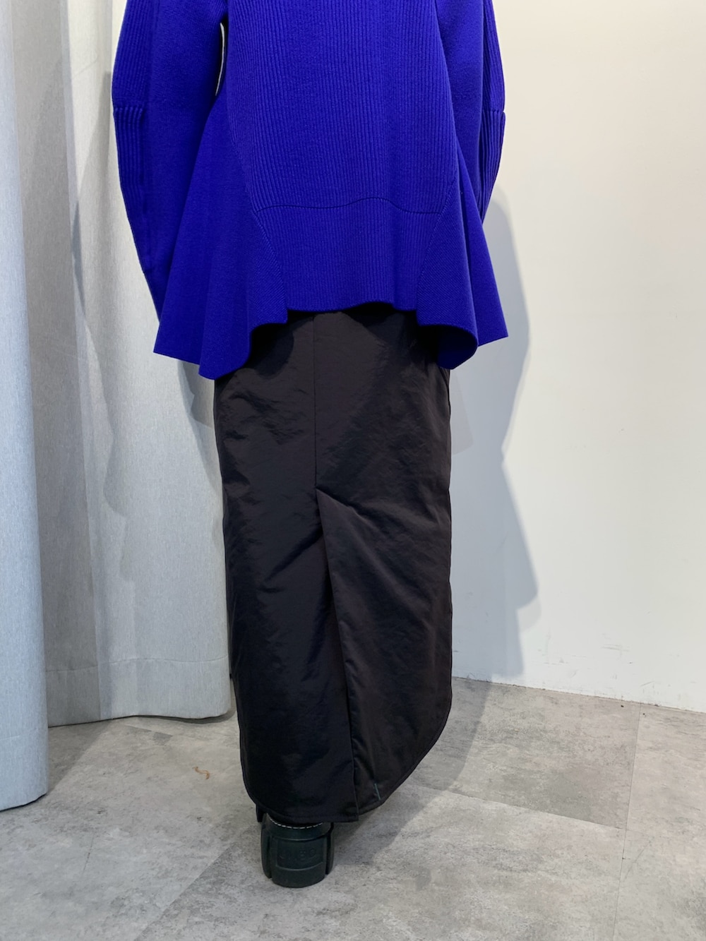 ブラック系のニット/セーター、ブラック系のスカート、ブラック系のブーツを着用したレディースの夏コーディネートの4枚目の写真