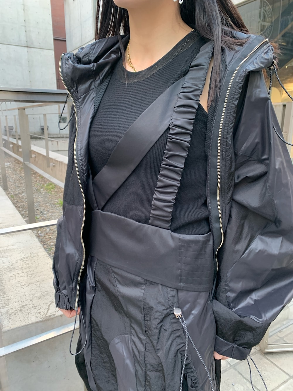 ブラック系のナイロンジャケット、ブラック系のジャンパースカート、ブラック系のサンダルを着用したレディースの冬コーディネートの6枚目の写真