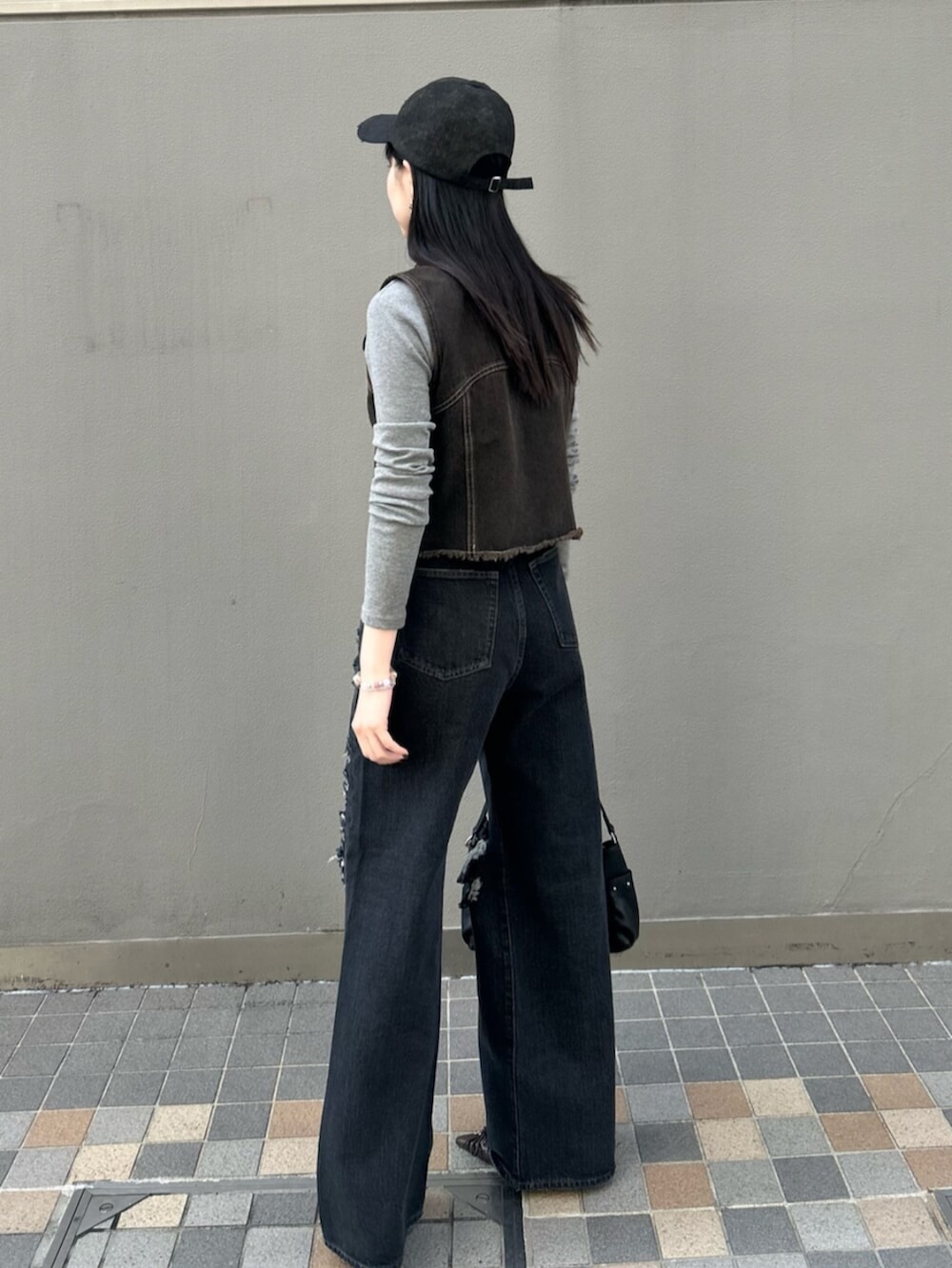 ブラック系のハンドバッグ、グレー系のTシャツ/カットソー、ブラック系のベストを着用したレディースの春コーディネートの3枚目の写真