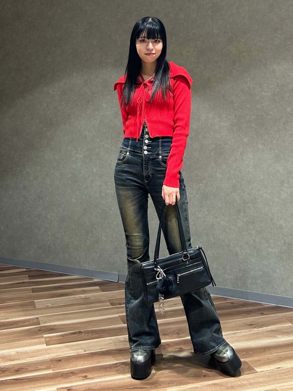 レッド系のニット/セーター、ブルー系のデニムパンツ、ブラック系のショルダーバッグを着用したレディースの秋コーディネートの2枚目の写真