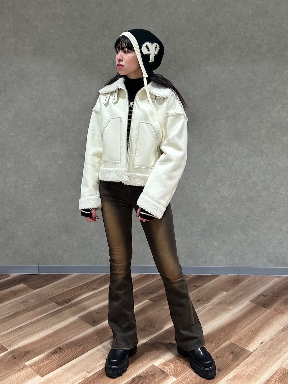 ホワイト系のブルゾン、ブラック系のブーツ、ブラック系のニット/セーターを着用したレディースの冬コーディネートの2枚目の写真