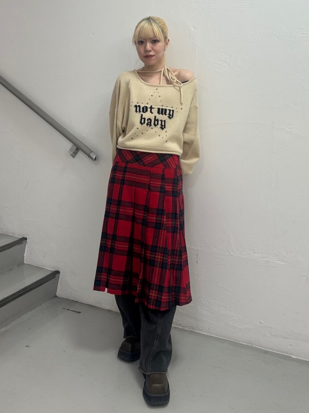 ブラック系のデニムパンツ、ブラウン系のブーツ、ホワイト系のニット/セーターを着用したレディースの冬コーディネートの2枚目の写真