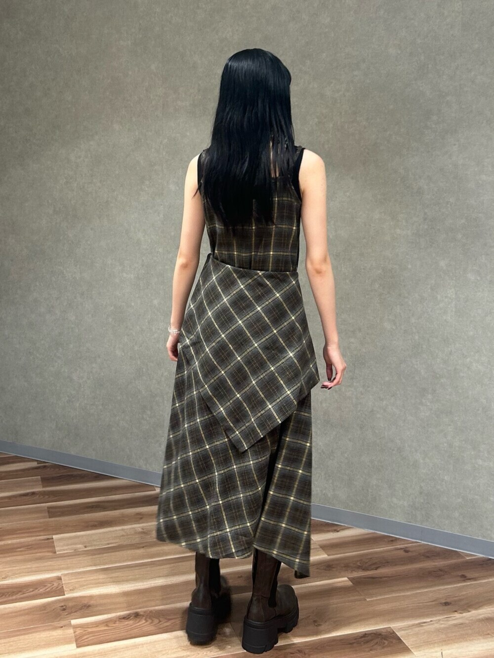 ブラック系のニット/セーター、グリーン系のワンピース、ブラウン系のブーツを着用したレディースの夏コーディネートの4枚目の写真