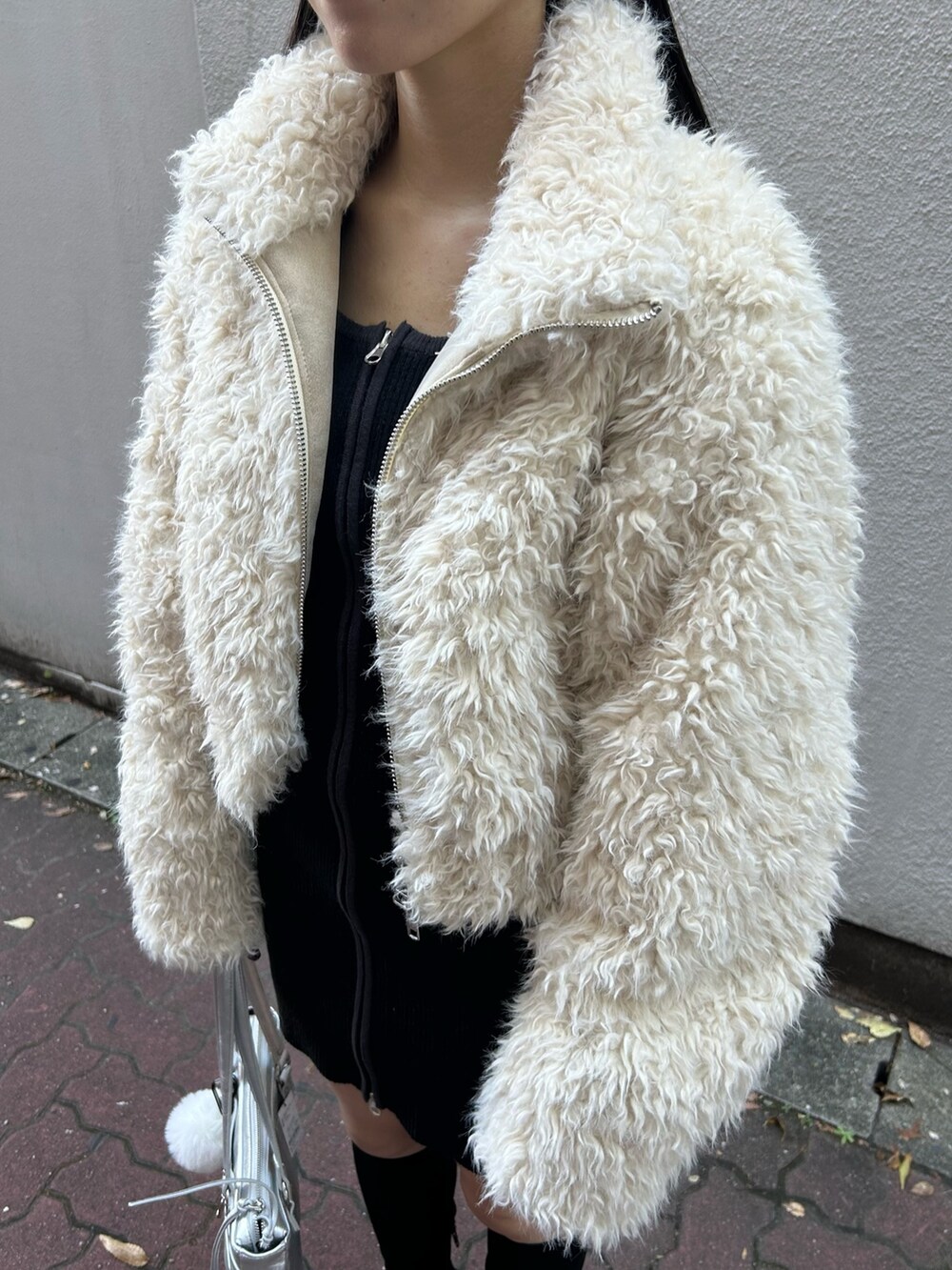 ホワイト系のブルゾン、ブラック系のワンピース、シルバー系のショルダーバッグを着用したレディースの秋コーディネートの5枚目の写真