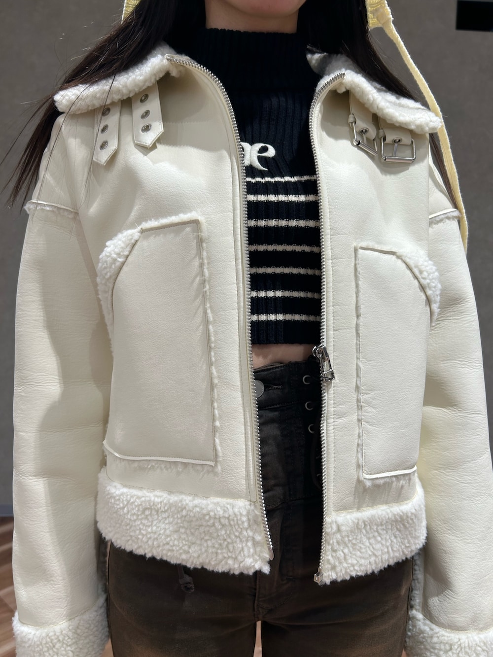 ホワイト系のブルゾン、ブラック系のブーツ、ブラック系のニット/セーターを着用したレディースの冬コーディネートの5枚目の写真