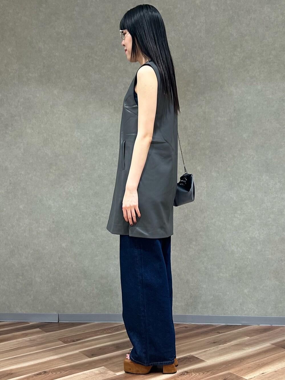 グレー系のワンピース、グレー系のハンドバッグ、ブルー系のデニムパンツを着用したレディースの夏コーディネートの3枚目の写真