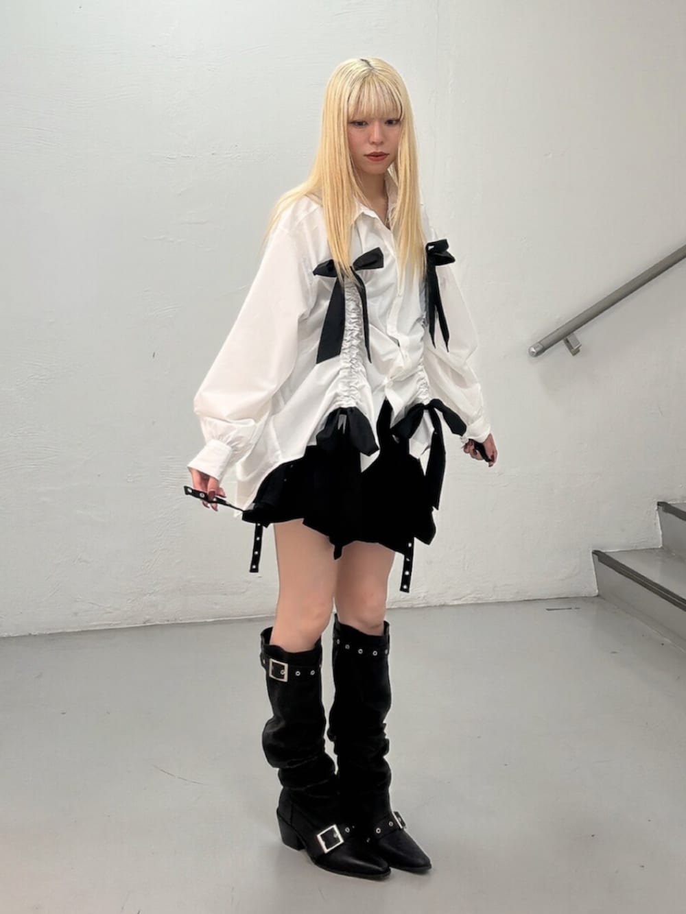 ブラック系のスカート、ブラック系のブーツ、ホワイト系のシャツ/ブラウスを着用したレディースの春コーディネートの2枚目の写真