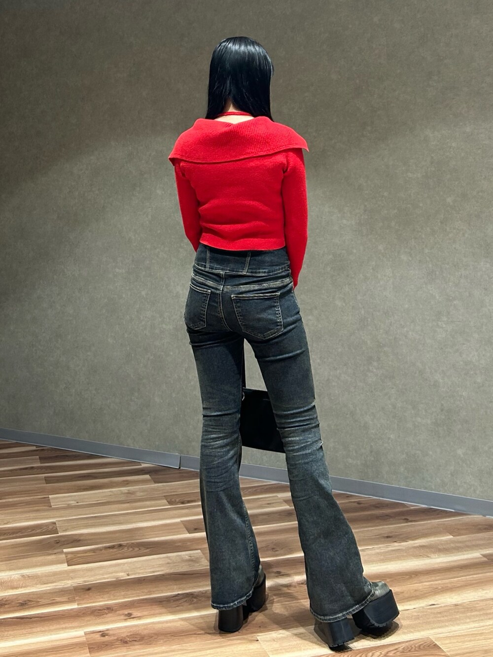 レッド系のニット/セーター、ブルー系のデニムパンツ、ブラック系のショルダーバッグを着用したレディースの秋コーディネートの4枚目の写真