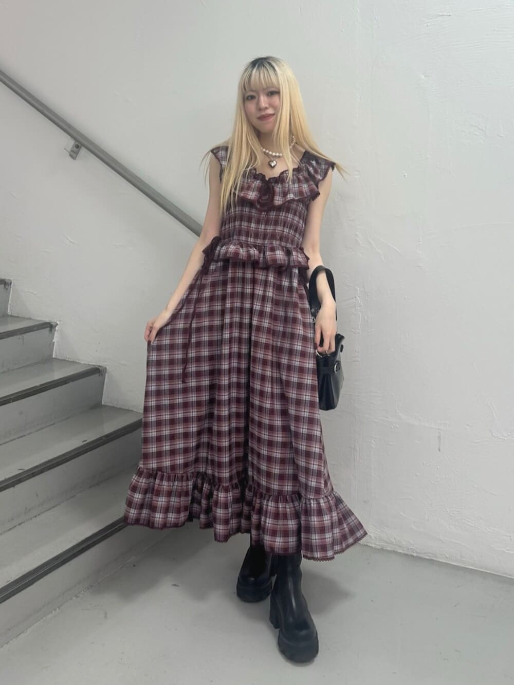 ブラック系のハンドバッグ、レッド系のワンピース、シルバー系のネックレスを着用したレディースの春コーディネートの2枚目の写真