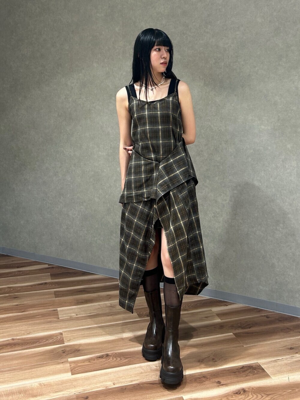 ブラック系のニット/セーター、グリーン系のワンピース、ブラウン系のブーツを着用したレディースの夏コーディネートの2枚目の写真