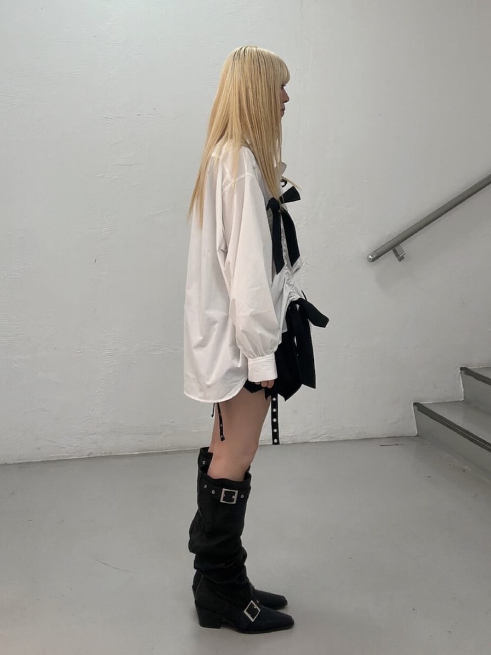 ブラック系のスカート、ブラック系のブーツ、ホワイト系のシャツ/ブラウスを着用したレディースの春コーディネートの3枚目の写真