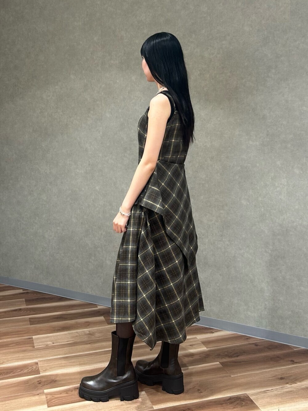 ブラック系のニット/セーター、グリーン系のワンピース、ブラウン系のブーツを着用したレディースの夏コーディネートの3枚目の写真