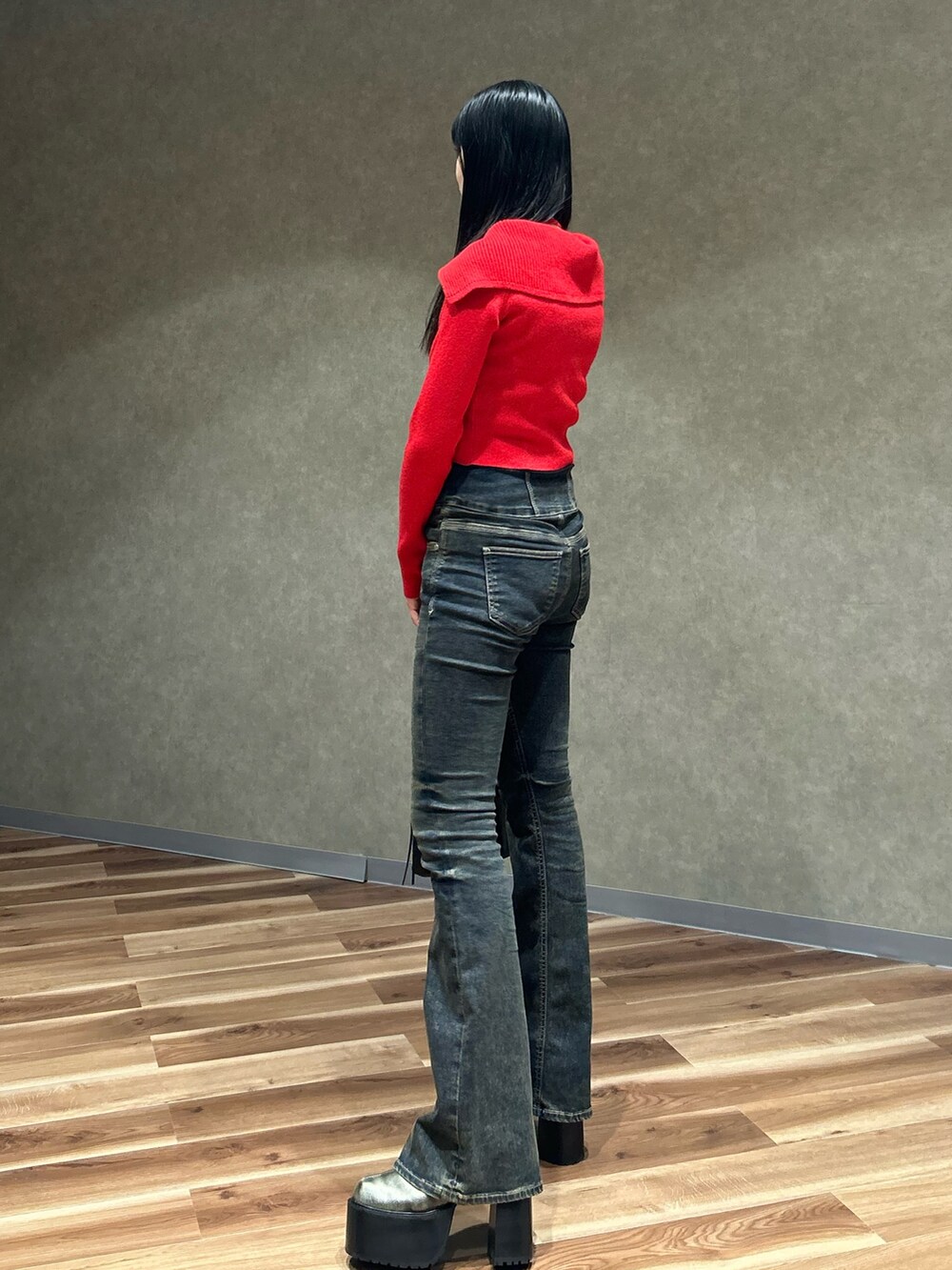 レッド系のニット/セーター、ブルー系のデニムパンツ、ブラック系のショルダーバッグを着用したレディースの秋コーディネートの3枚目の写真