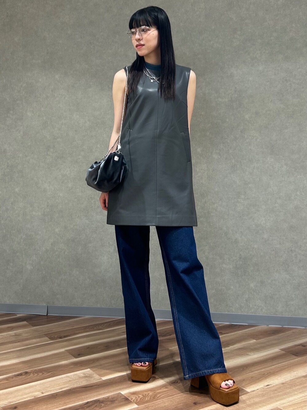 グレー系のワンピース、グレー系のハンドバッグ、ブルー系のデニムパンツを着用したレディースの夏コーディネートの2枚目の写真