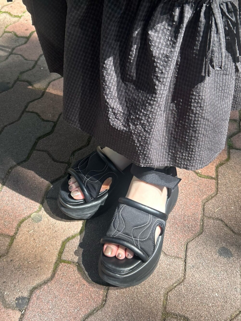 ブラック系のサンダル、ブラウン系のTシャツ/カットソー、ブルー系のデニムパンツを着用したレディースの夏コーディネートの7枚目の写真