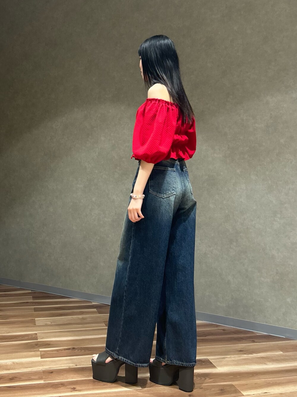 レッド系のTシャツ/カットソー、ブルー系のデニムパンツ、グレー系のサンダルを着用したレディースの春コーディネートの2枚目の写真