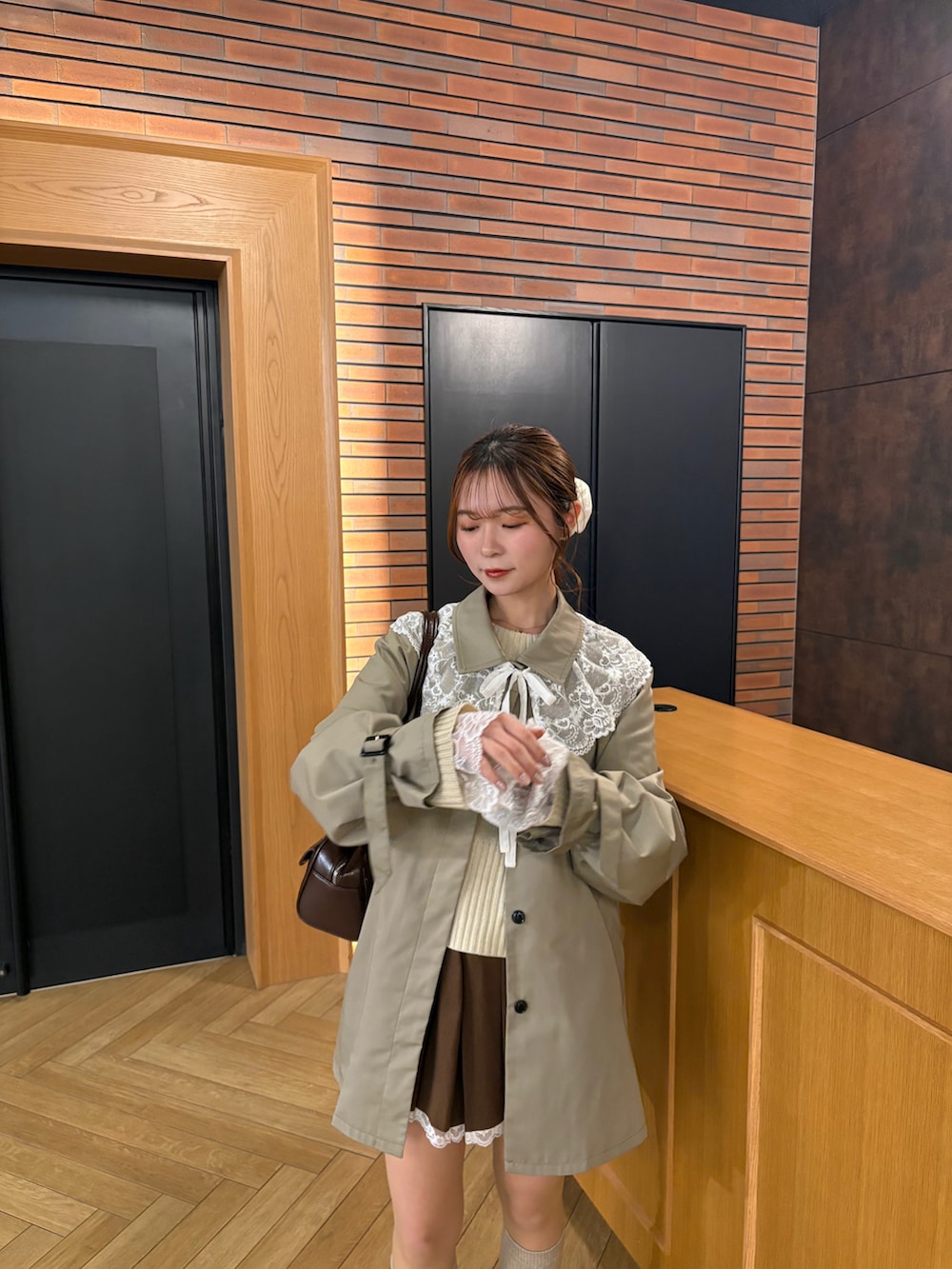 ブラウン系のシューズ、ブラウン系のスカート、グリーン系のトレンチコートを着用したレディースの春コーディネートの3枚目の写真