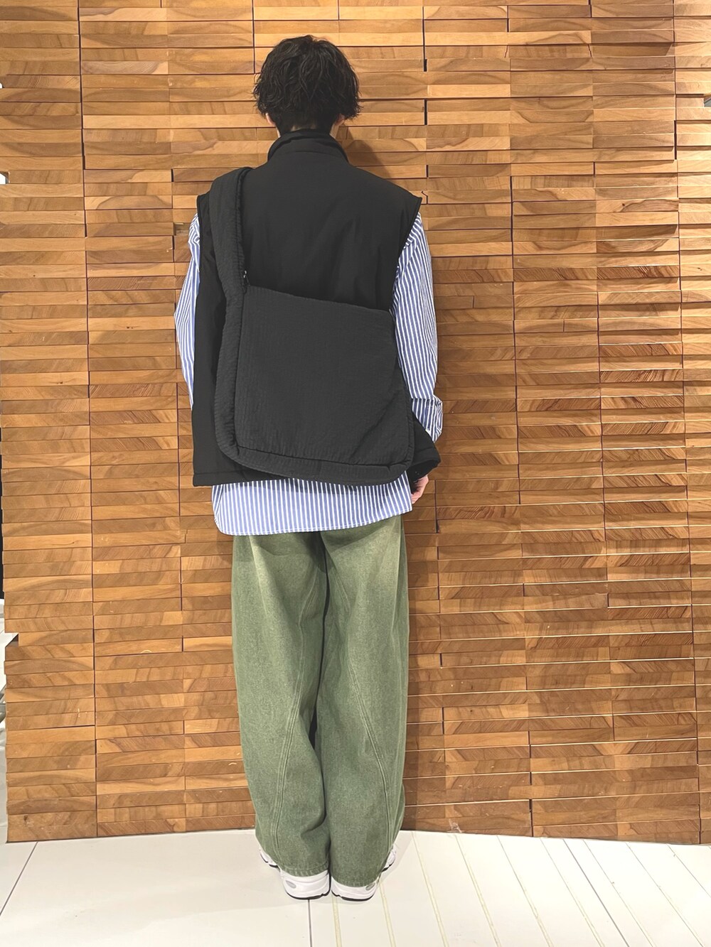 ブラック系のダウンベスト、ブルー系のシャツ/ブラウス、ブラック系のショルダーバッグを着用したメンズの秋コーディネートの4枚目の写真