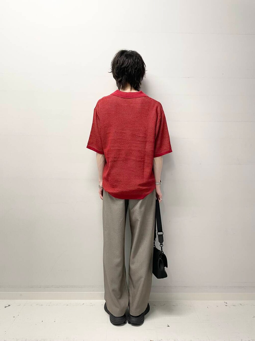 レッド系のニット/セーター、ブラック系のショルダーバッグ、ブラウン系のその他パンツを着用したメンズの春コーディネートの3枚目の写真