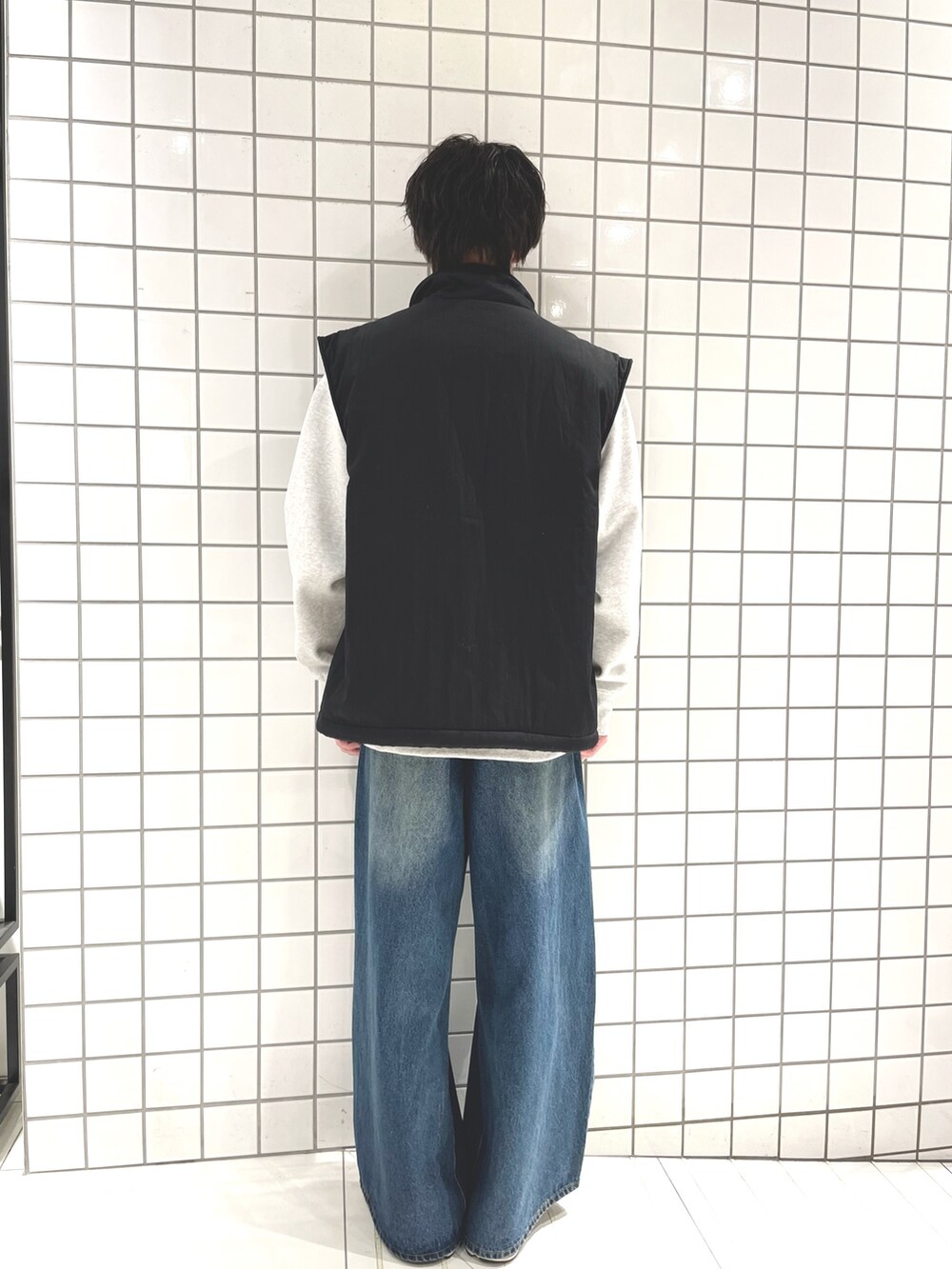 グレー系のスウェット、ブラック系のダウンベスト、ブルー系のデニムパンツを着用したメンズの冬コーディネートの3枚目の写真