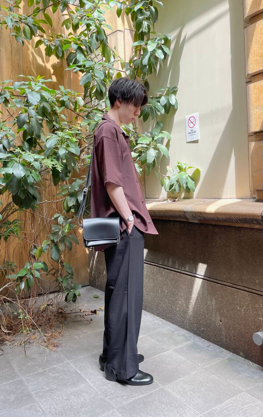 ブラック系のその他シューズ、ブラック系のスラックス、ホワイト系のTシャツ/カットソーを着用したメンズの夏コーディネートの2枚目の写真