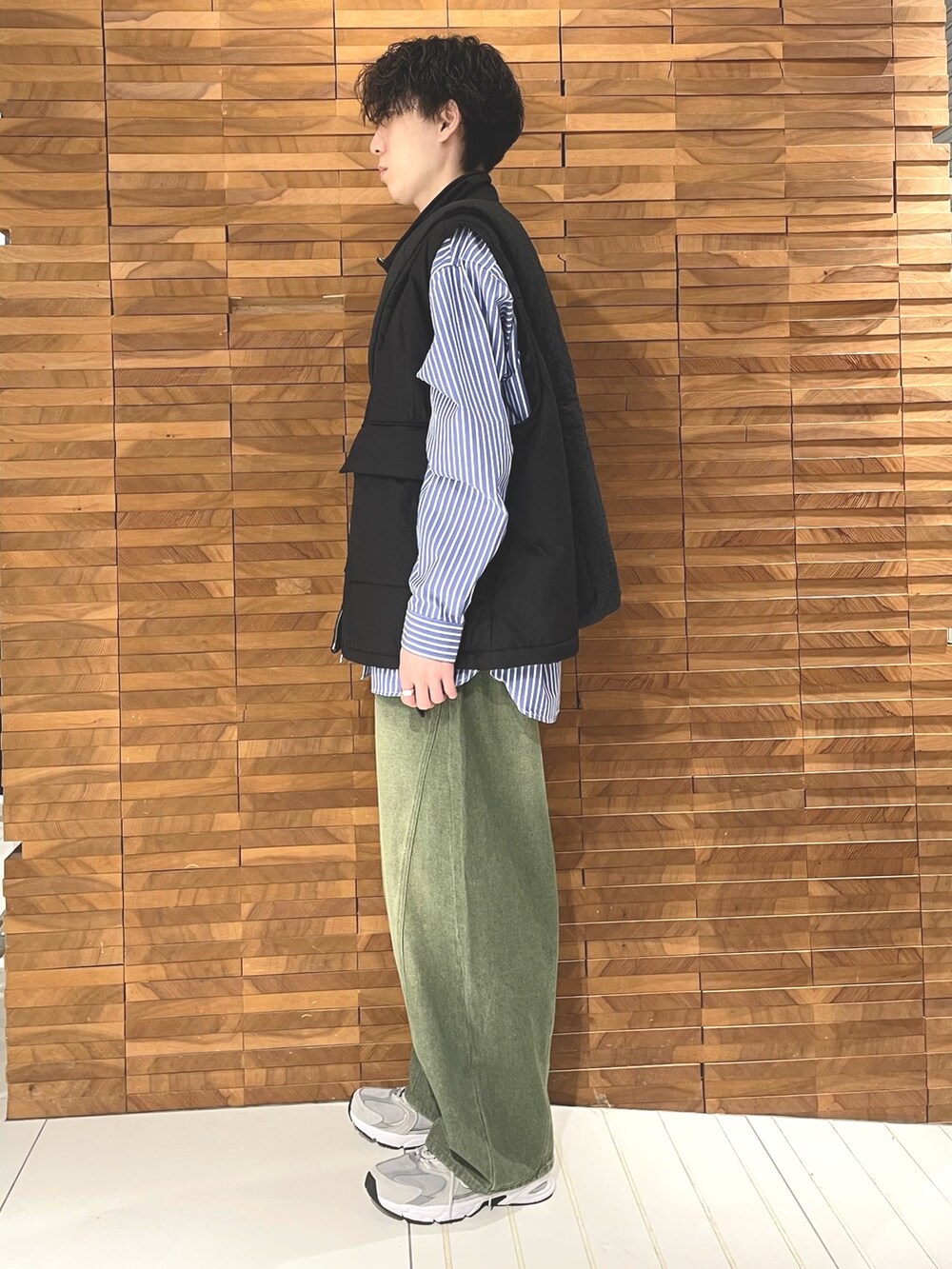 ブラック系のダウンベスト、ブルー系のシャツ/ブラウス、ブラック系のショルダーバッグを着用したメンズの秋コーディネートの3枚目の写真