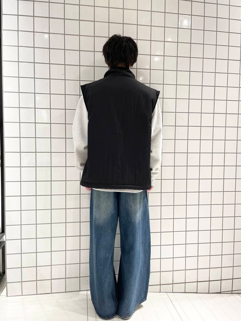 ブラック系のダウンベスト、ブルー系のデニムパンツ、グレー系のスウェットを着用したメンズの冬コーディネートの3枚目の写真