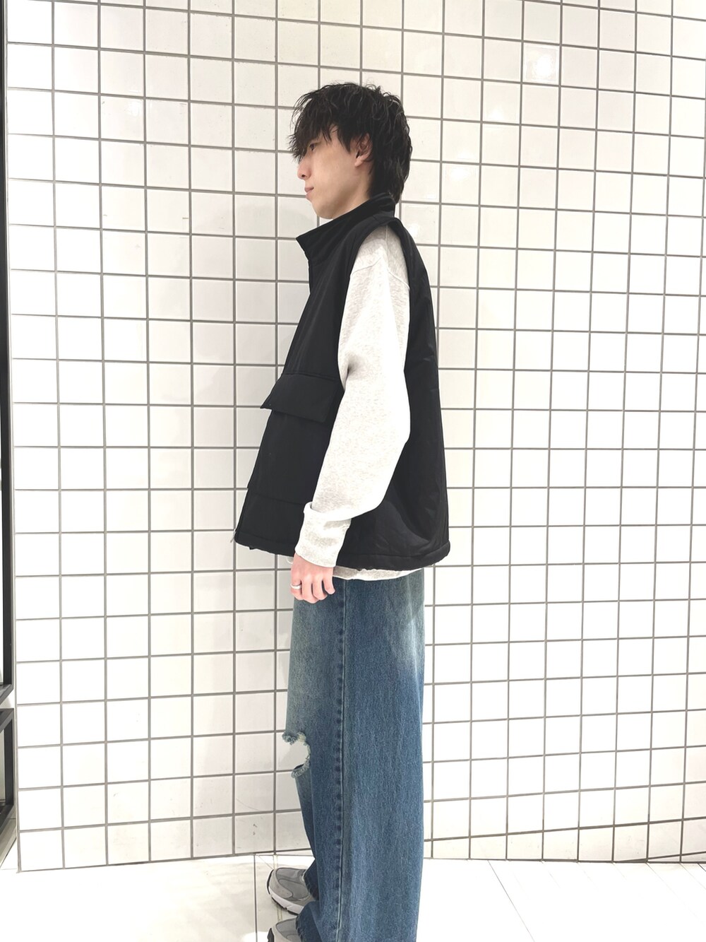 グレー系のスウェット、ブラック系のダウンベスト、ブルー系のデニムパンツを着用したメンズの冬コーディネートの2枚目の写真