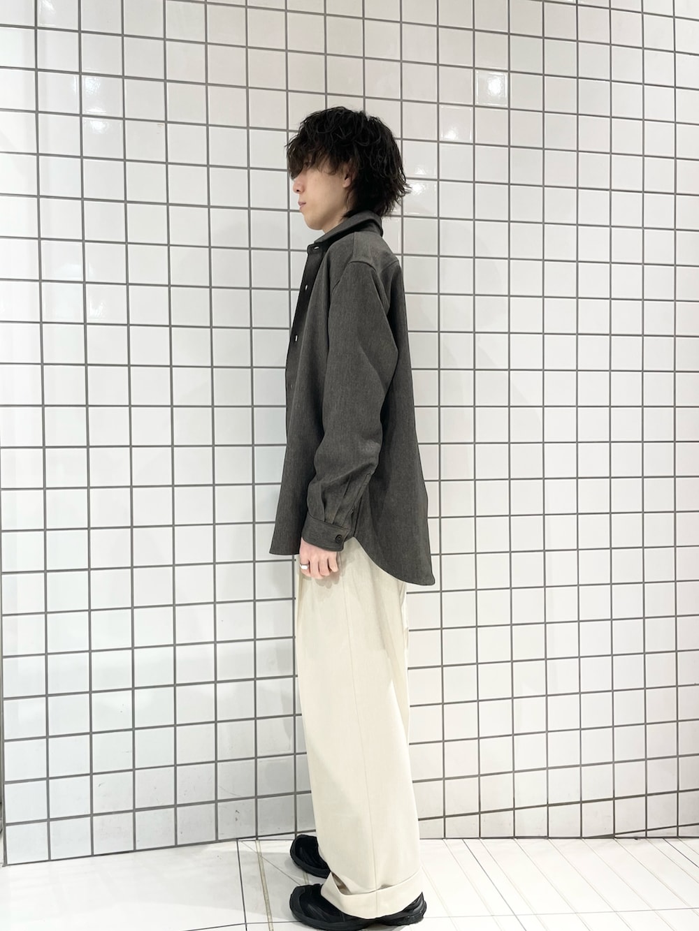 ベージュ系のスラックス、グリーン系のシャツ/ブラウス、ブラック系のニット/セーターを着用したメンズの冬コーディネートの2枚目の写真