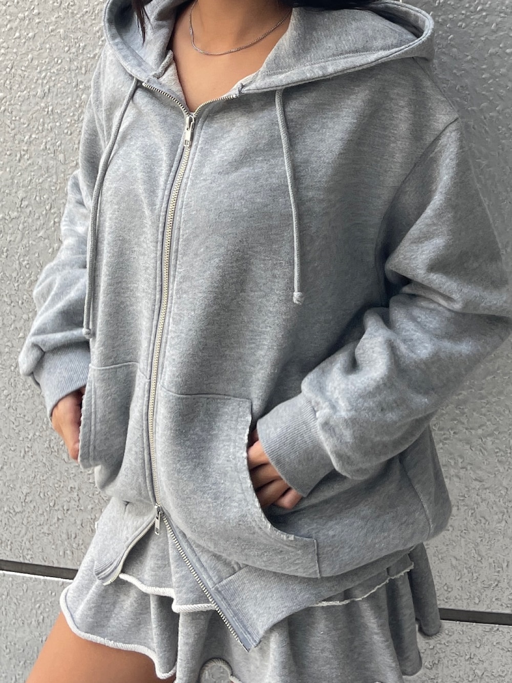 グレー系のパーカー、グレー系のスカート、ブラック系のブーツを着用したレディースの秋コーディネートの4枚目の写真