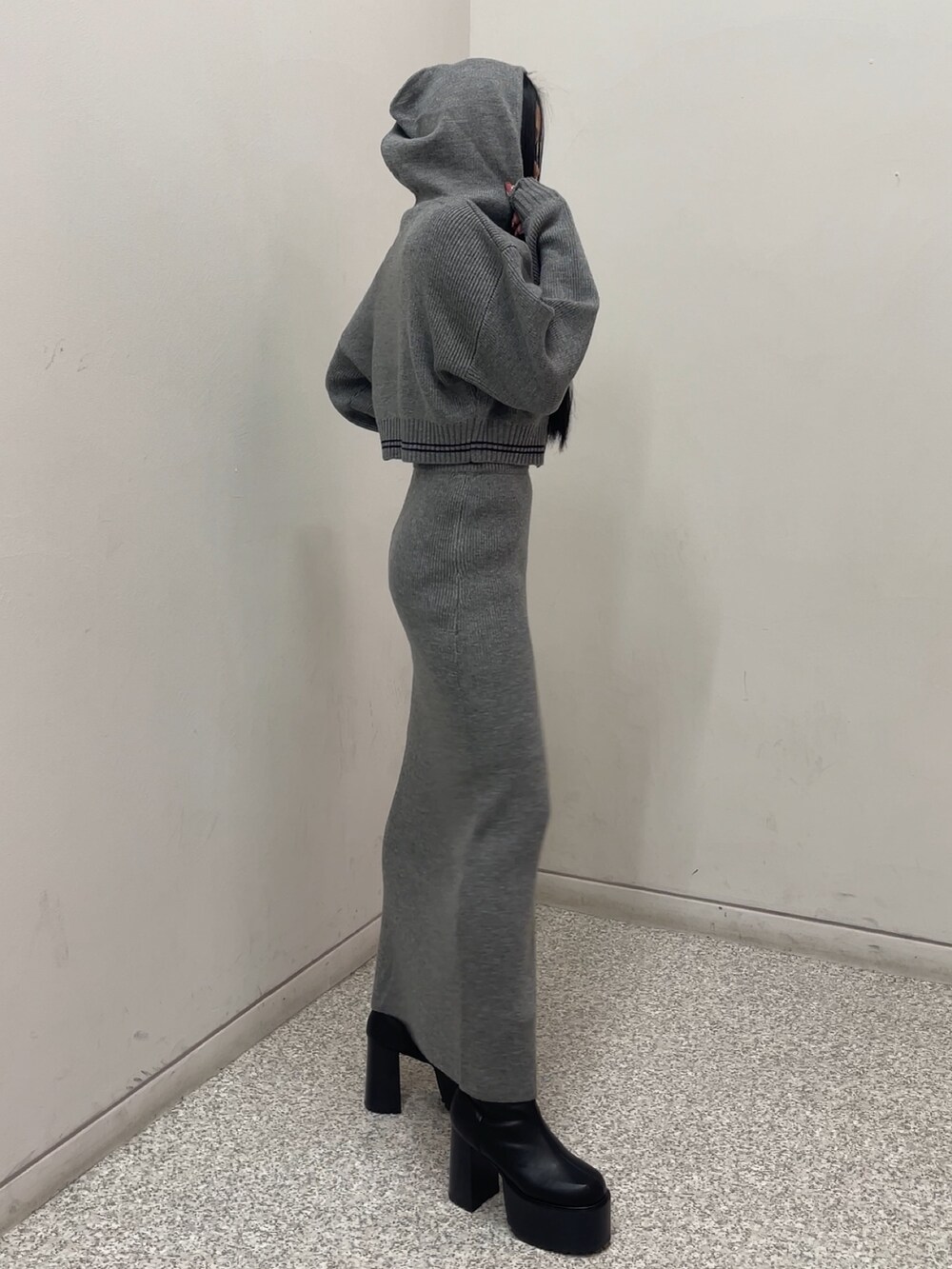 グレー系のスカート、グレー系のニット/セーター、ブラック系のブルゾンを着用したレディースの秋コーディネートの2枚目の写真