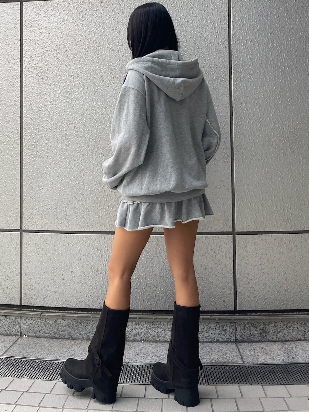グレー系のパーカー、グレー系のスカート、ブラック系のブーツを着用したレディースの秋コーディネートの2枚目の写真