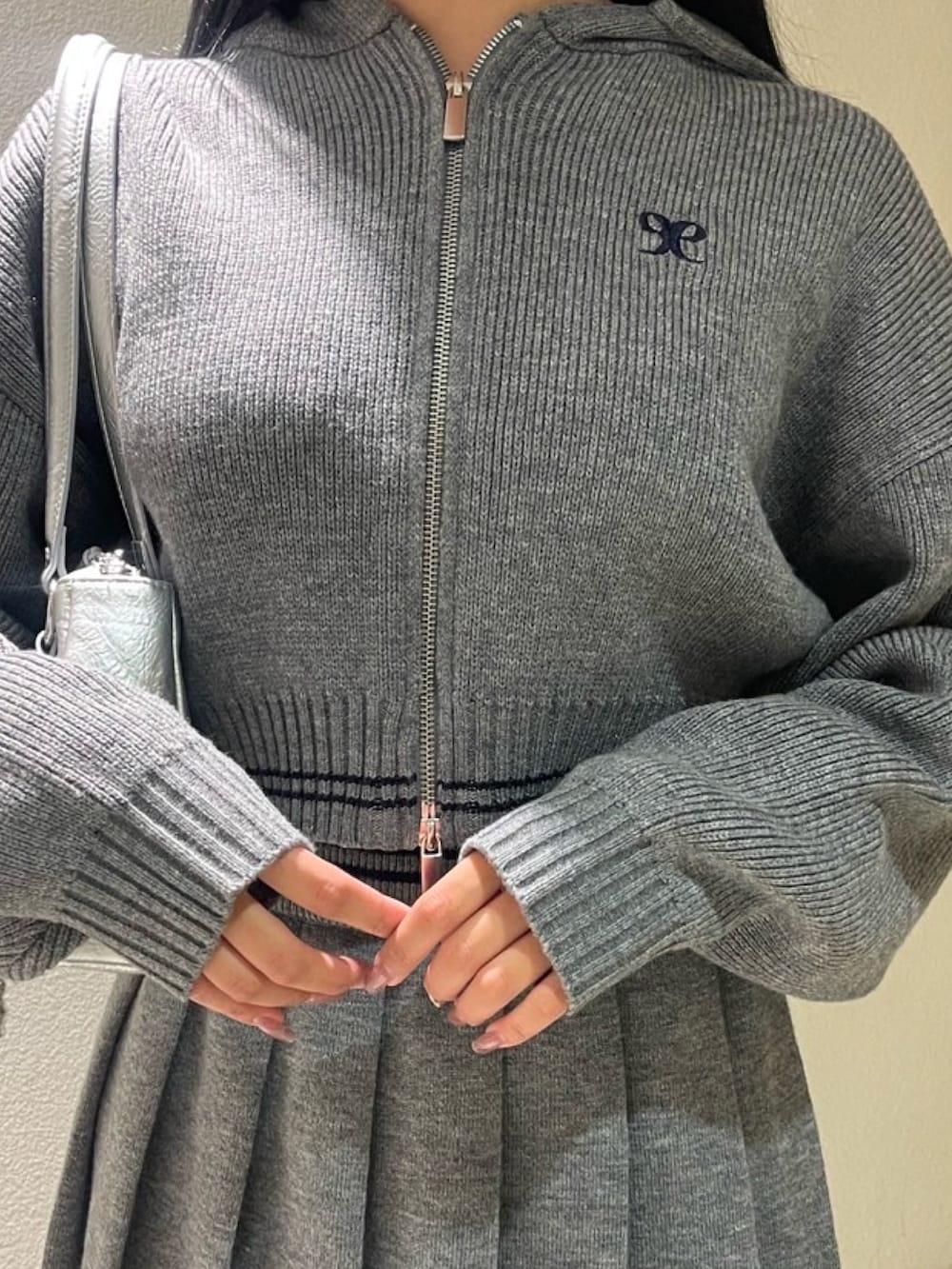 グレー系のスカート、グレー系のニット/セーター、ブラック系のブルゾンを着用したレディースの秋コーディネートの4枚目の写真