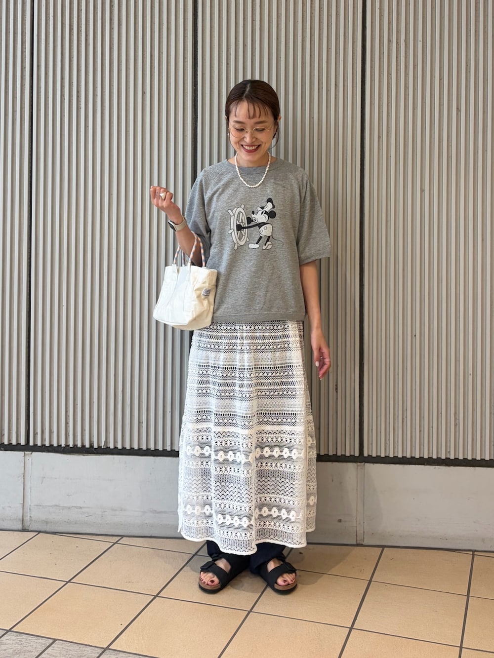 グレー系のシャツ/ブラウス、ホワイト系のショルダーバッグ、ブラック系のサンダルを着用したレディースの夏コーディネートの3枚目の写真