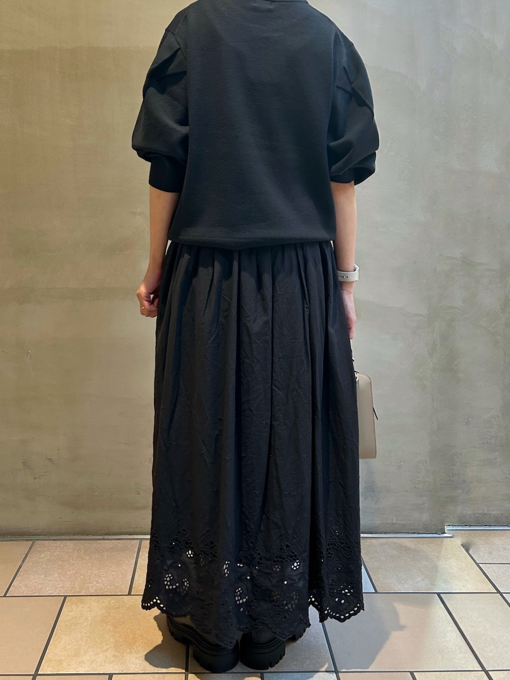 ブラック系のニット/セーター、ブラック系のスカート、レッド系のショルダーバッグを着用したレディースの秋コーディネートの4枚目の写真