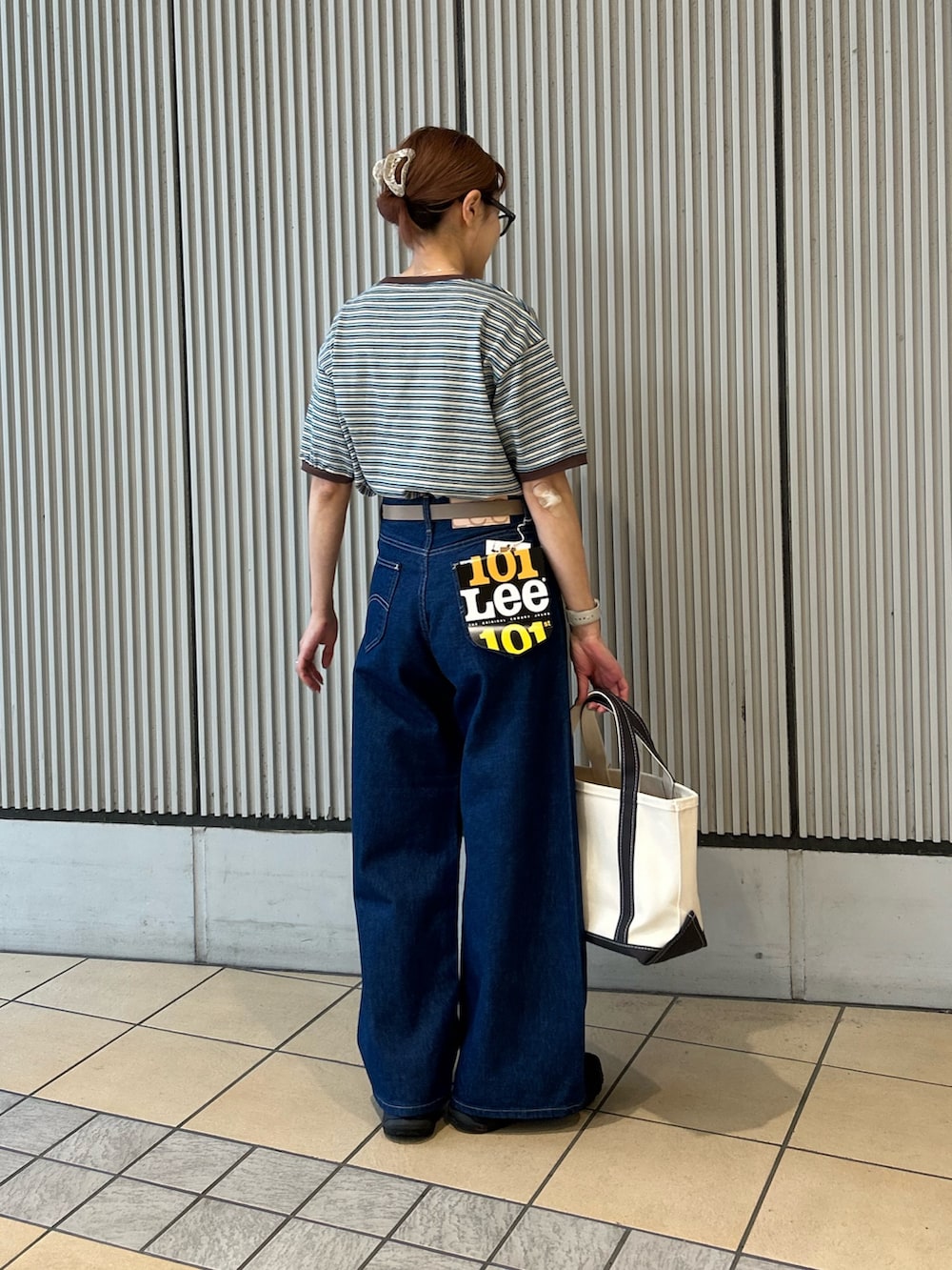 ホワイト系のトートバッグ、ブルー系のデニムパンツ、ブルー系のTシャツ/カットソーを着用したレディースの春コーディネートの2枚目の写真