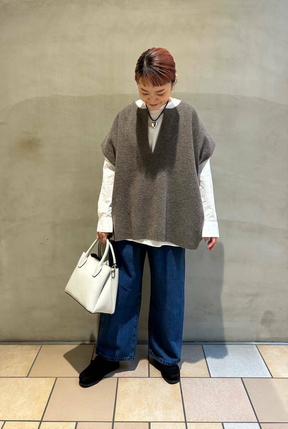 ブラック系のブーツ、ホワイト系のショルダーバッグ、ブルー系のデニムパンツを着用したレディースの冬コーディネートの3枚目の写真