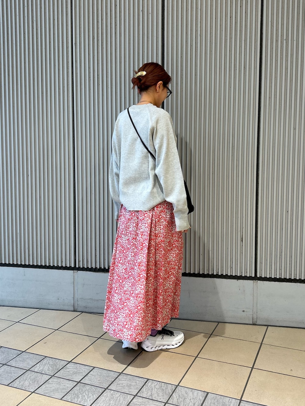 レッド系のスカート、グレー系のニット/セーター、ブラック系のスニーカーを着用したレディースの春コーディネートの2枚目の写真