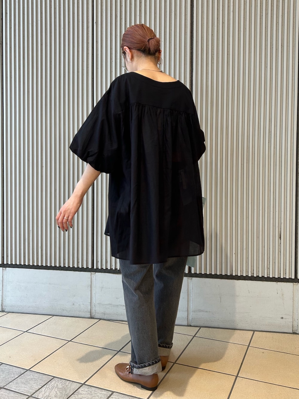 ブラック系のチュニック、ブラック系のデニムパンツを着用したレディースの夏コーディネートの2枚目の写真