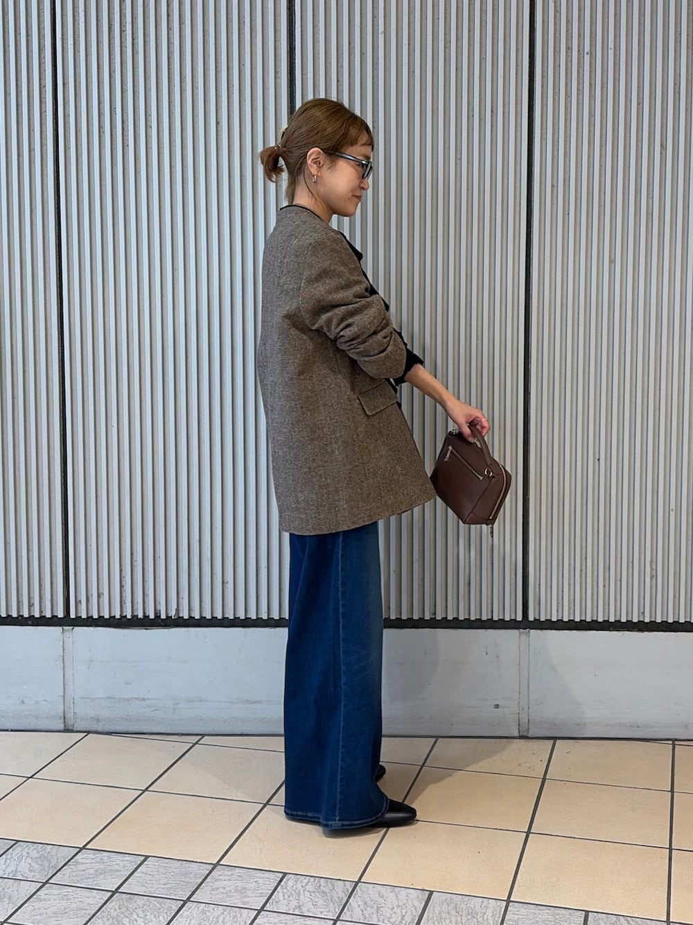 ブルー系のデニムパンツ、ブラウン系のノーカラージャケット、ブラック系のシャツ/ブラウスを着用したレディースの秋コーディネートの2枚目の写真