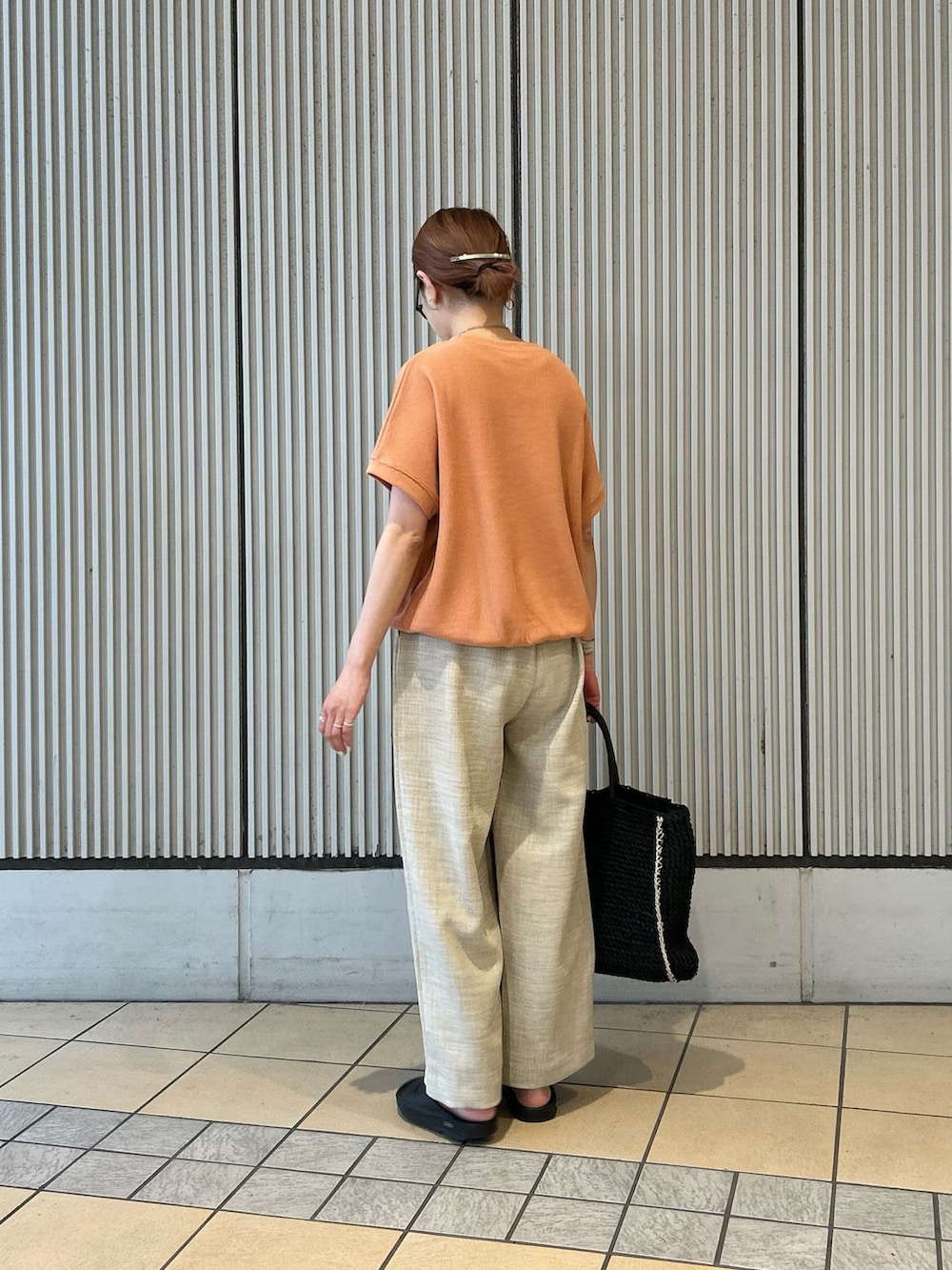 オレンジ系のTシャツ/カットソー、ベージュ系のその他パンツ、ブラック系のトートバッグを着用したレディースの春コーディネートの2枚目の写真