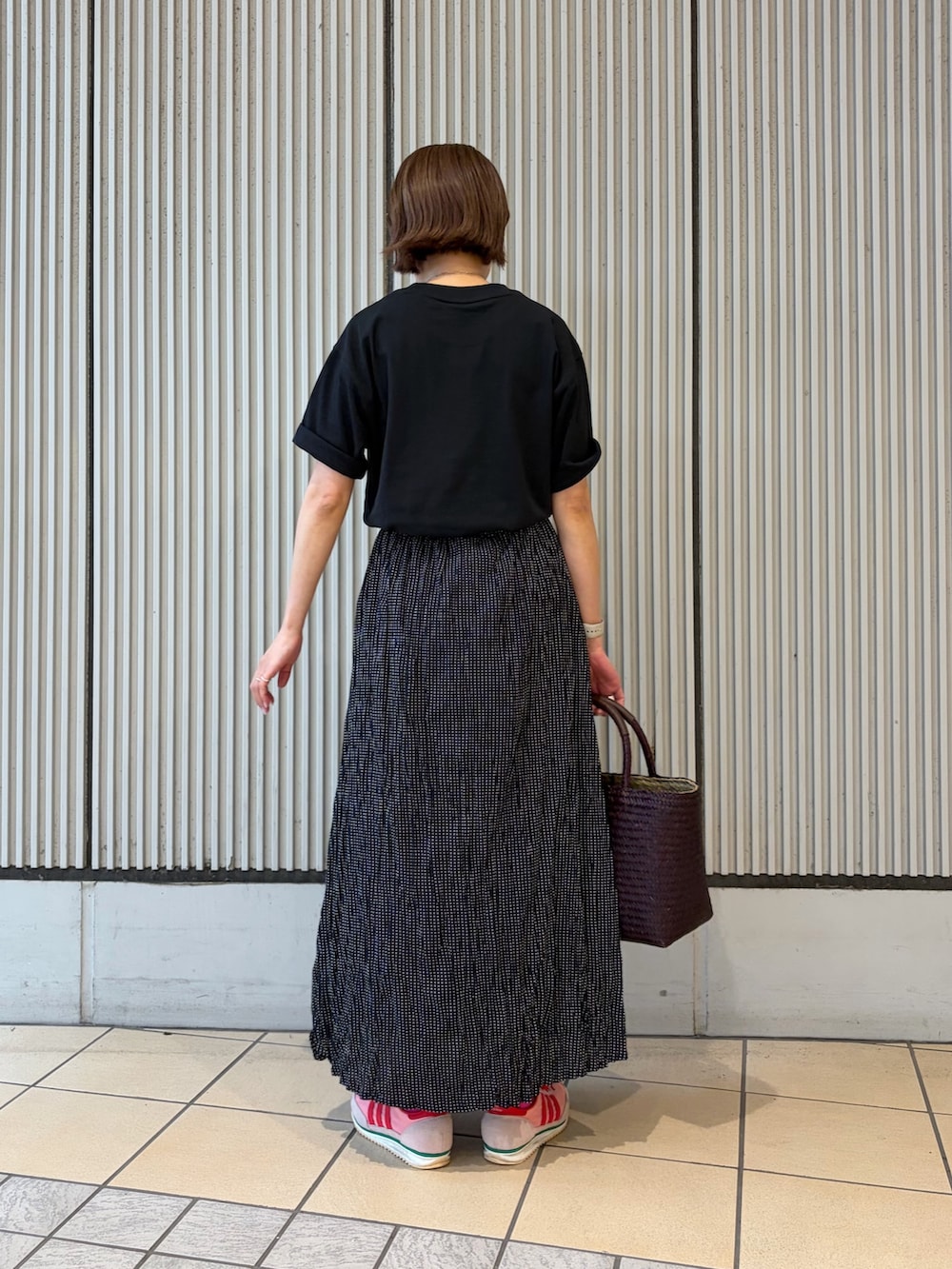 ブラック系のTシャツ/カットソー、ブラック系のスカート、レッド系のトートバッグを着用したレディースの夏コーディネートの3枚目の写真