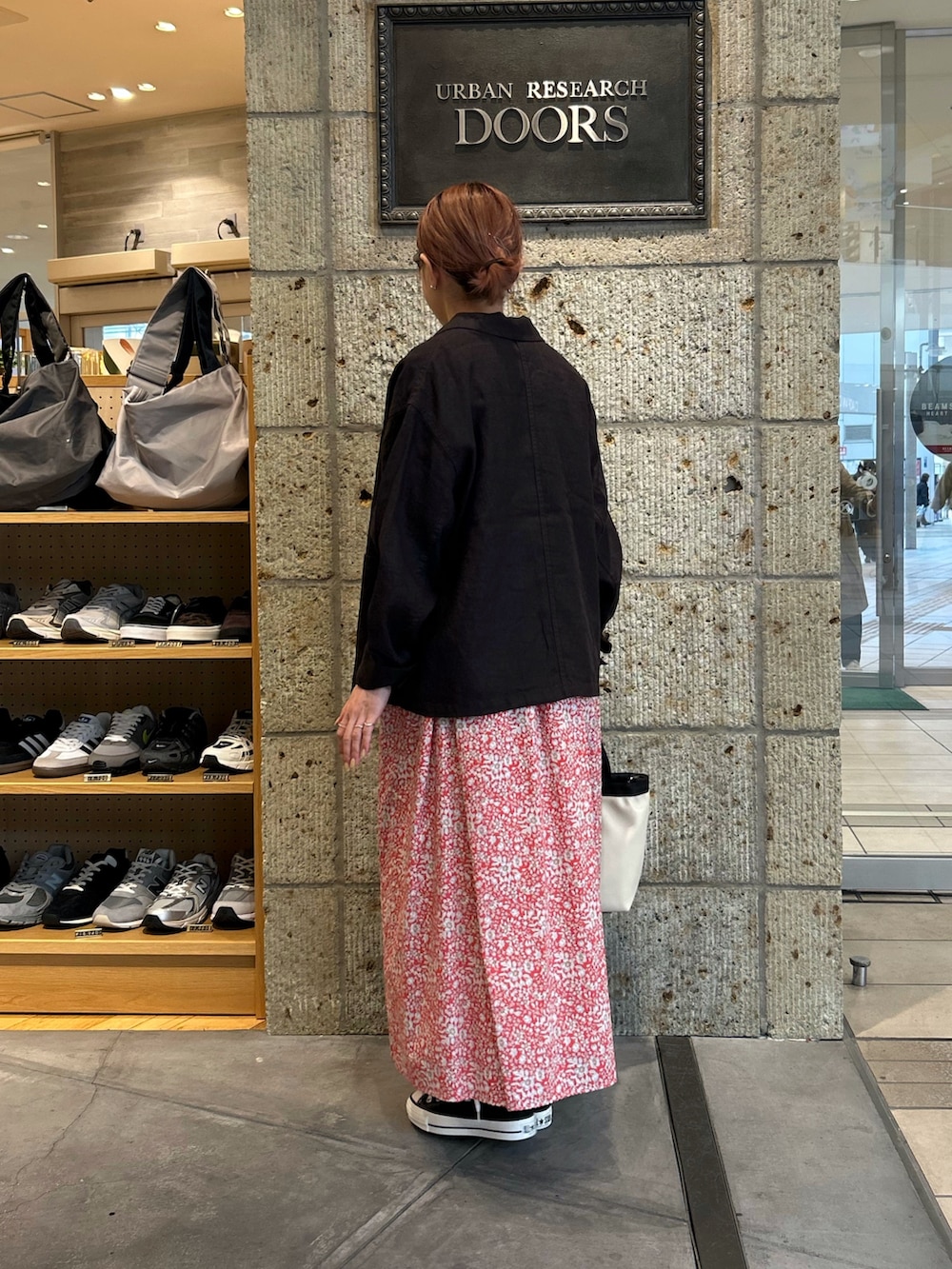 レッド系のスカート、ブラック系のスニーカー、ホワイト系のハンドバッグを着用したレディースの春コーディネートの2枚目の写真