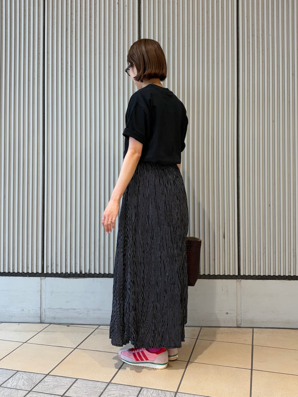ブラック系のTシャツ/カットソー、ブラック系のスカート、レッド系のトートバッグを着用したレディースの夏コーディネートの2枚目の写真